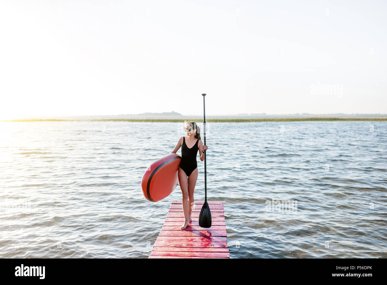 Frau mit paddleboard auf der Pier im Freien Stockfoto