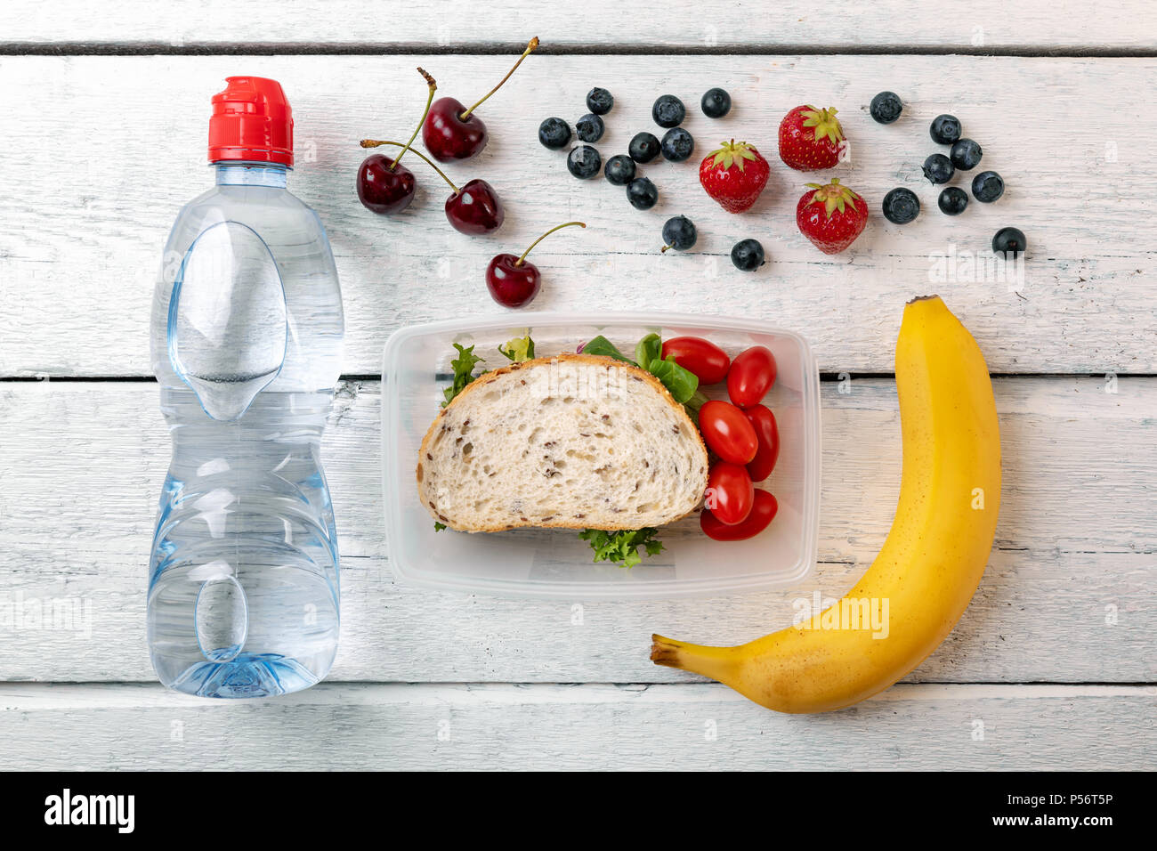 Lunchpaket mit Obst und Wasser Flasche auf weiße Holztisch Stockfoto