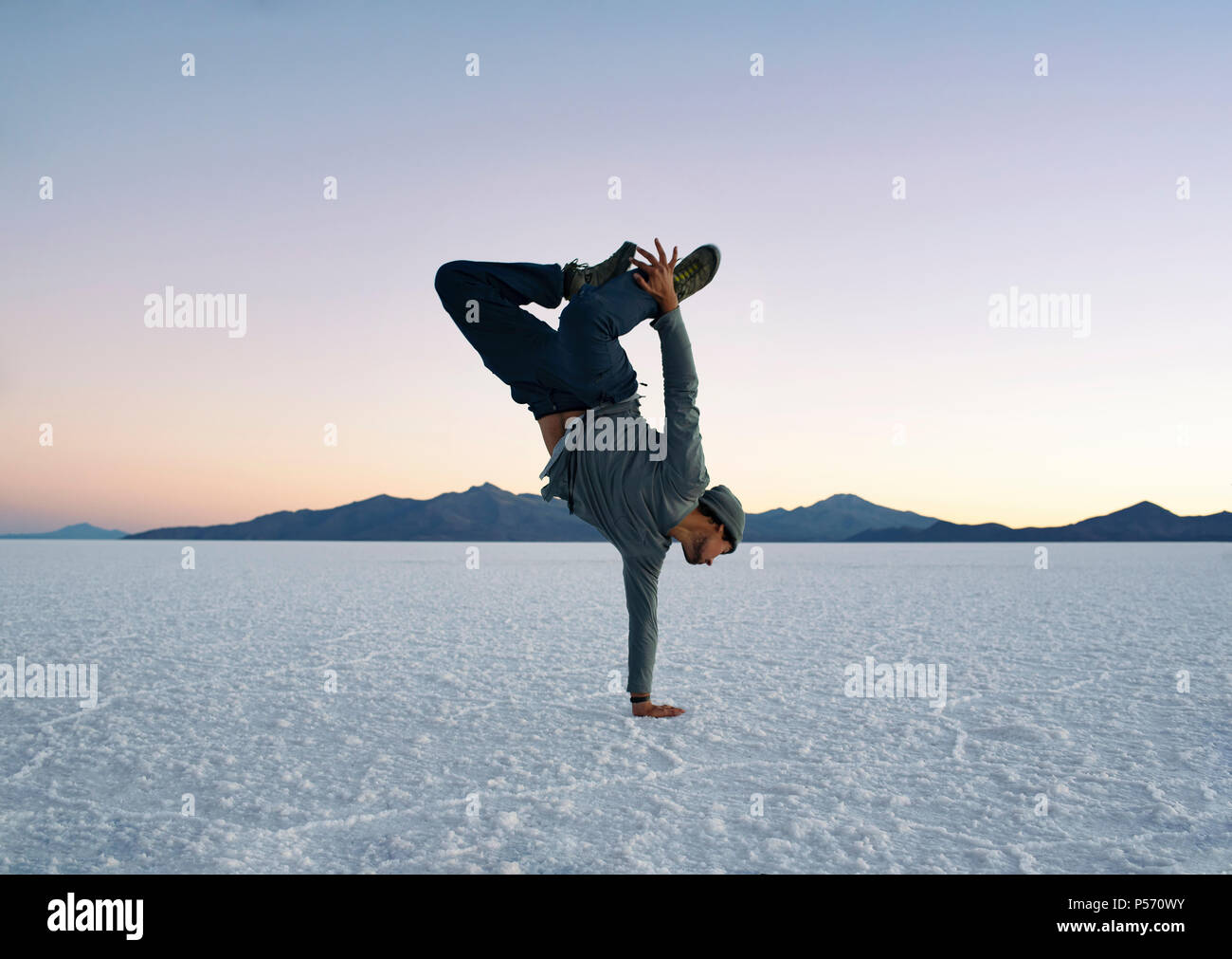 Junge tun einen Arm handstand während des Sonnenuntergangs. Salar de Uyuni (salzsee), Bolivien. Aktiver Lebensstil, Tanz, Fitness, Abenteuer. Jun 2018 Stockfoto