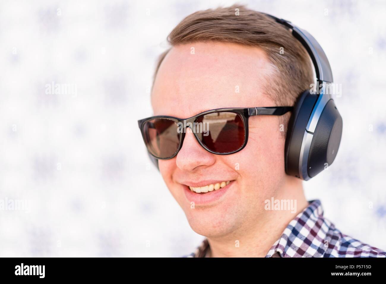 Der junge Mann hört etwas nettes zu und lächelt mit den Ohrhörern. Stockfoto