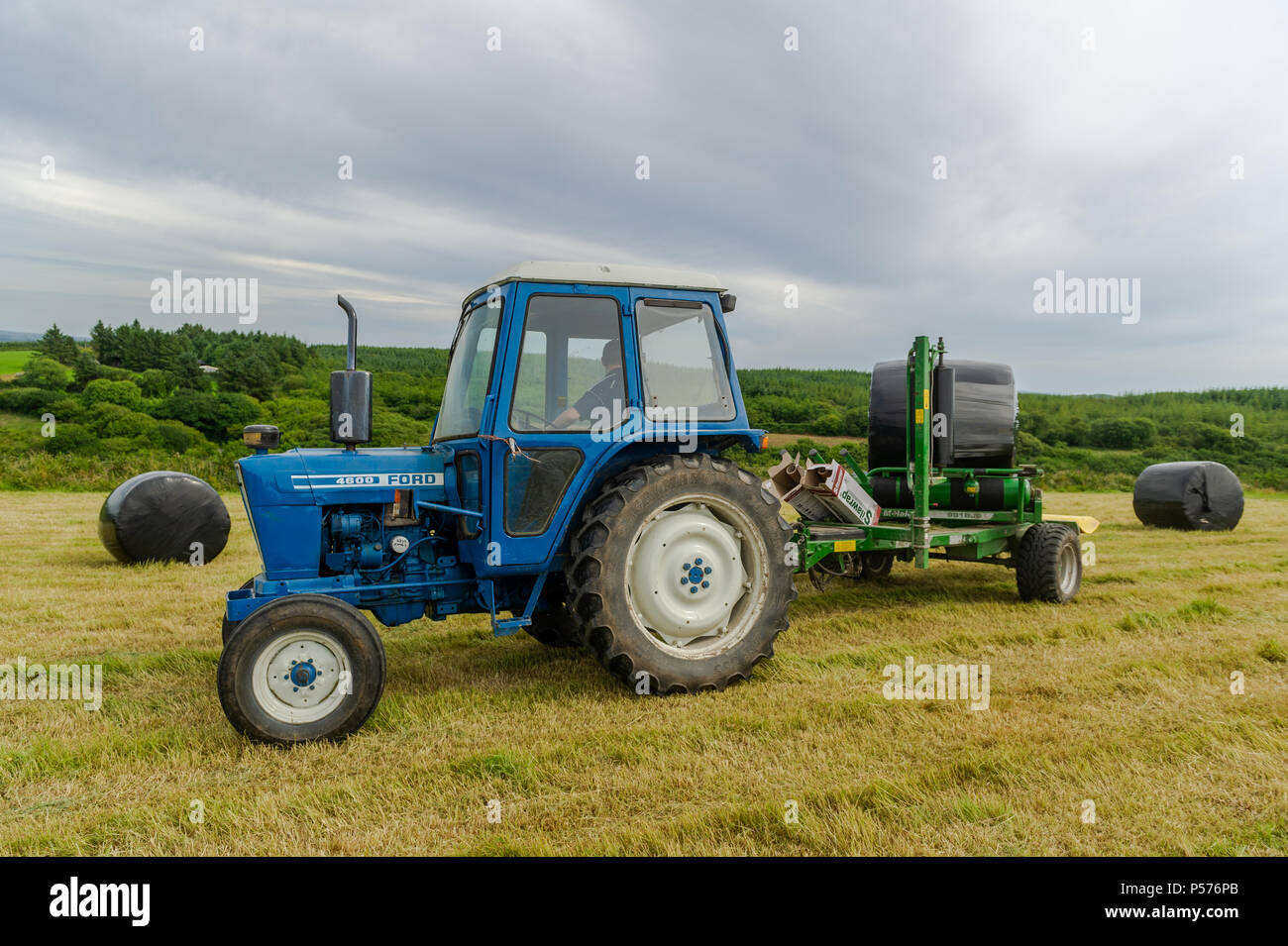Ballydehob, West Cork, Irland. 25. Juni 2018. Alan Pyburn von Hollum John O'Driscoll Silage Auftragnehmern auf der Grundlage wickelt eine silage Kaution auf das ballydehob Bauernhof von Ben Deane auf einem sehr warmen Tag. Dies ist der Auftakt zu einer Mini-Hitzewelle, in der Temperaturen gesetzt sind, zu erreichen 31°Grad Celsius bis Donnerstag dieser Woche. Credit: Andy Gibson/Alamy Leben Nachrichten. Stockfoto