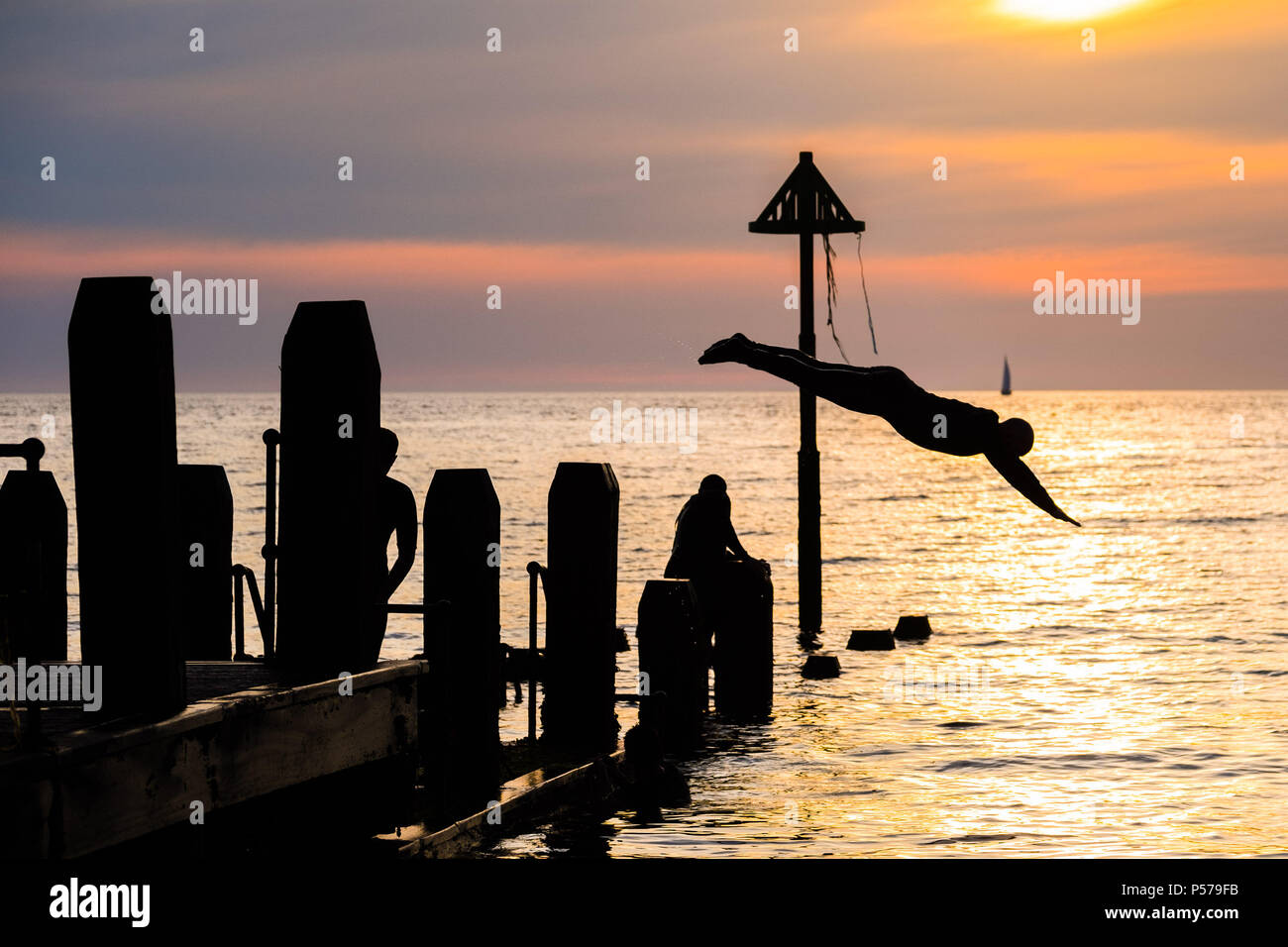 25. Juni 2018. Aberystwyth Wales UK UK Wetter: Eine Gruppe junger Leute in Silhouette ins Meer zusammen, vom Pier am Clearwater Beach in der Dämmerung springen am Ende einer anderen glorreichen Tag der heißen Sonne ungebrochen. Das Vereinigte Königreich ist die Überschrift in eine mini Hitzewelle mit Temperaturen um 29° oder 30° Celsius bis Mitte der Woche Foto © Keith Morris Credit Hit: Keith Morris/Alamy leben Nachrichten Stockfoto