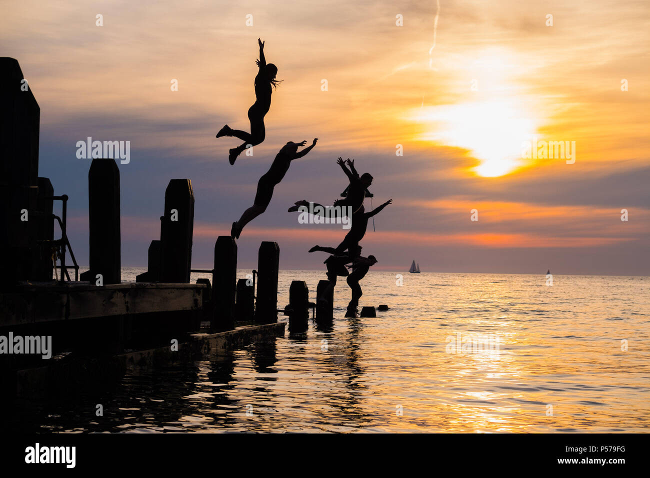 25. Juni 2018. Aberystwyth Wales UK UK Wetter: Eine Gruppe junger Leute in Silhouette ins Meer zusammen, vom Pier am Clearwater Beach in der Dämmerung springen am Ende einer anderen glorreichen Tag der heißen Sonne ungebrochen. Das Vereinigte Königreich ist die Überschrift in eine mini Hitzewelle mit Temperaturen um 29° oder 30° Celsius bis Mitte der Woche Foto © Keith Morris Credit Hit: Keith Morris/Alamy leben Nachrichten Stockfoto