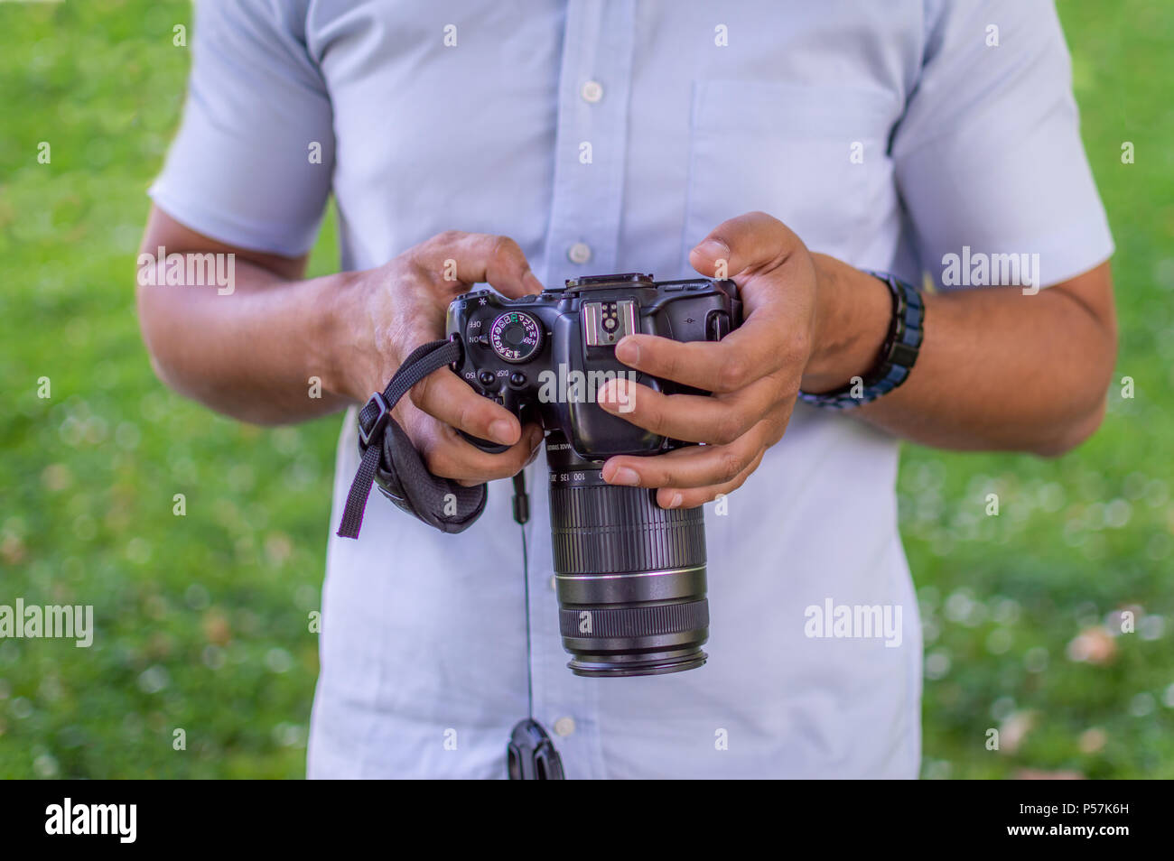 Eine Person mit seiner DSLR-Kamera in einem Rasen oder Garten im Freien Stockfoto