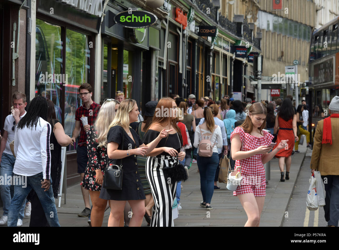 Käufer und Touristen zu Fuß entlang Magdalen Street, Oxford, wo High Street Einzelhändler wie Supermärkte Sainsbury's Lokale, Tesco Metro, der Schuh r Stockfoto