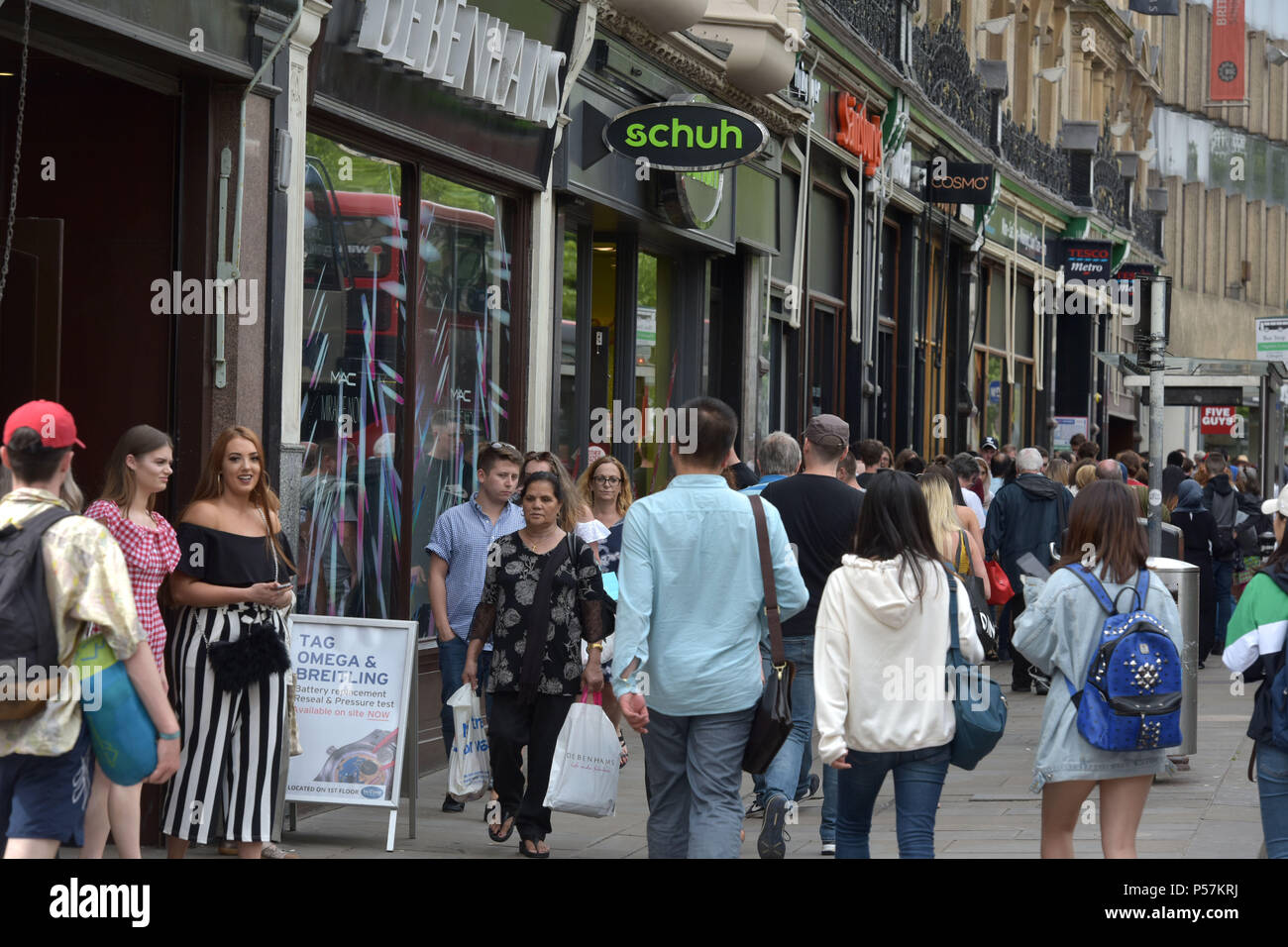 Käufer und Touristen zu Fuß entlang Magdalen Street, Oxford, wo High Street Einzelhändler wie Supermärkte Sainsbury's Lokale, Tesco Metro, der Schuh r Stockfoto