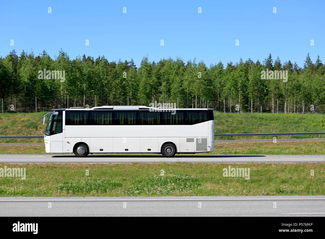 Weiß Coach bus Fahrt auf der Autobahn an einem sonnigen Tag des Sommers, Seitenansicht. Stockfoto