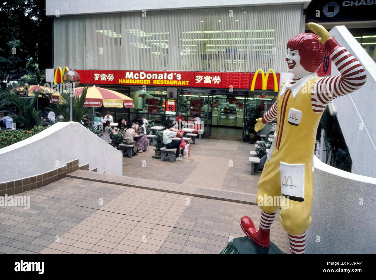 Ronald McDonald, die ikonische rothaarigen Clown, dass ist der berühmte Werbung Symbol für einen weltweiten Fast-Food-Kette, begrüßt die hungernden Völker zu einem McDonald's Restaurant in Singapur in Südostasien. Es ist eines von sieben Standorten der Hamburger Kette entlang der eleganten Einkaufsstraße Orchard Road. Ronald wurde als Maskottchen der amerikanischen Firma im Jahr 1963 eingeführt und Jetzt lächelt Diners, die an mehr als 35.000 McDonald's Restaurants in über 100 Ländern. Stockfoto