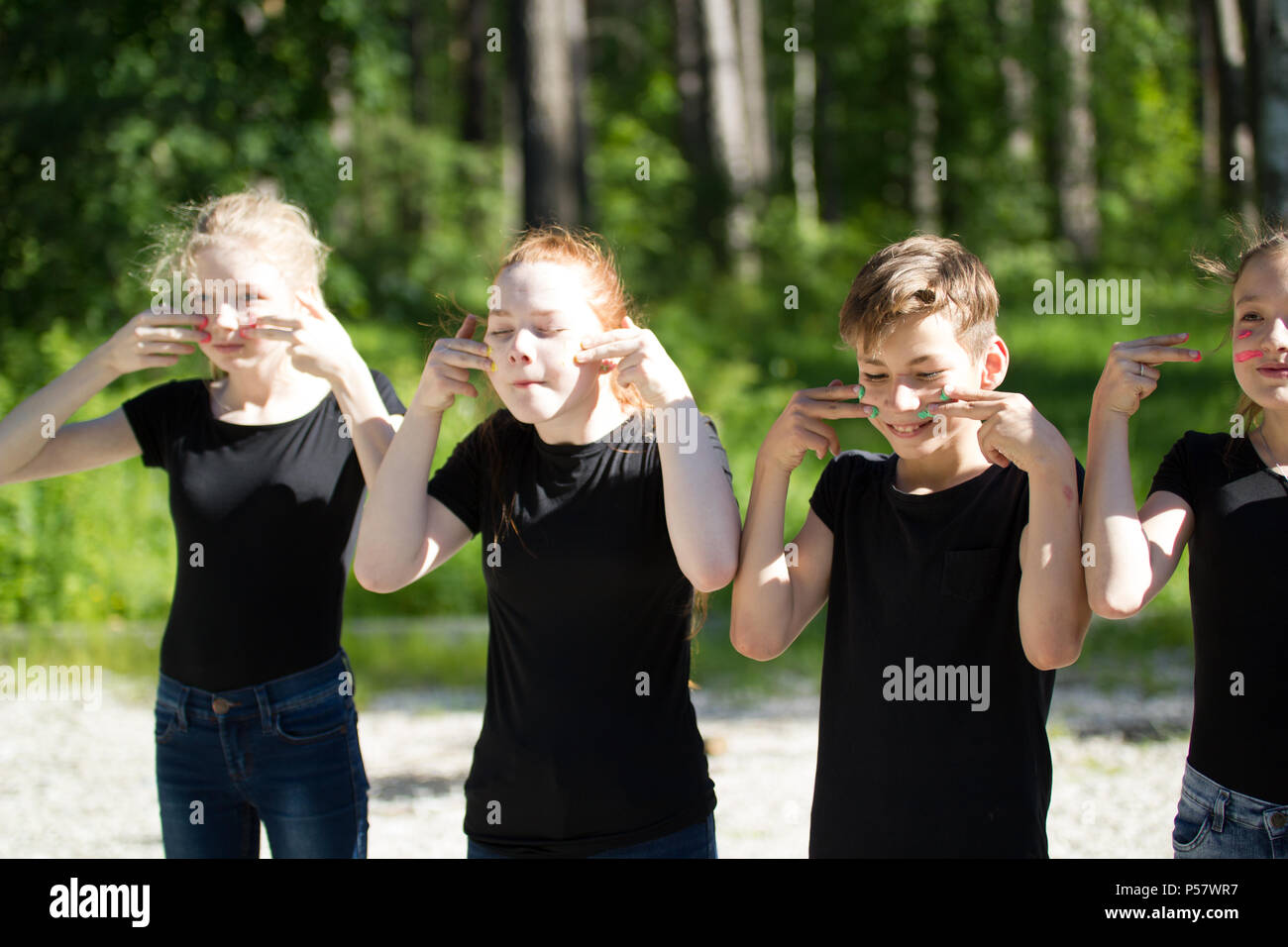 Gruppe von Teenagern in schwarzen T-Shirts malen ihre Gesichter Spaß im Freien an einem sonnigen Tag Stockfoto
