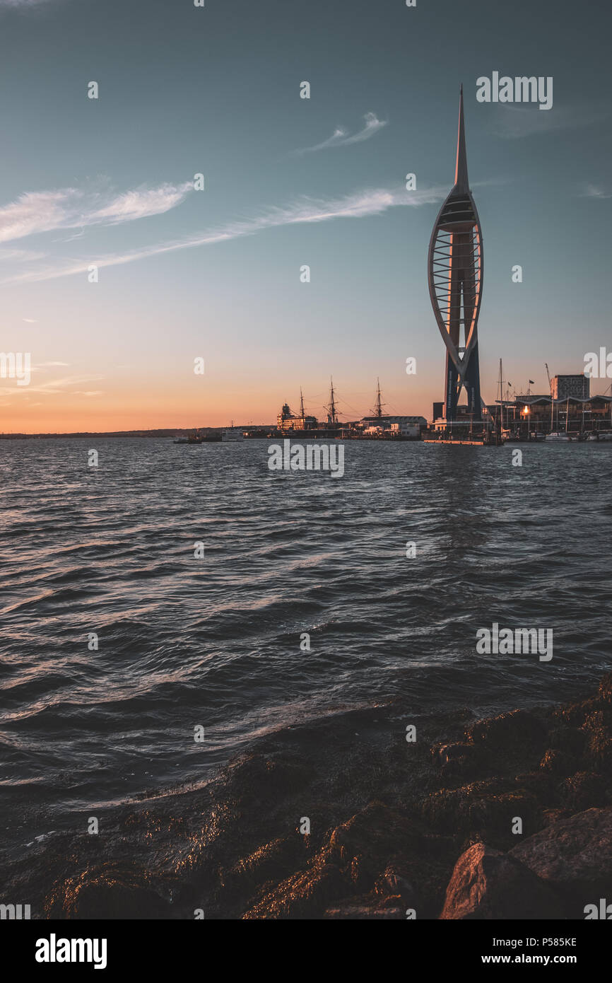 Blick über das Wasser zu Spinnekar Turm auf Gunwharf Quays in Portsmouth bei Sonnenuntergang mit Felsen im Vordergrund. Stockfoto