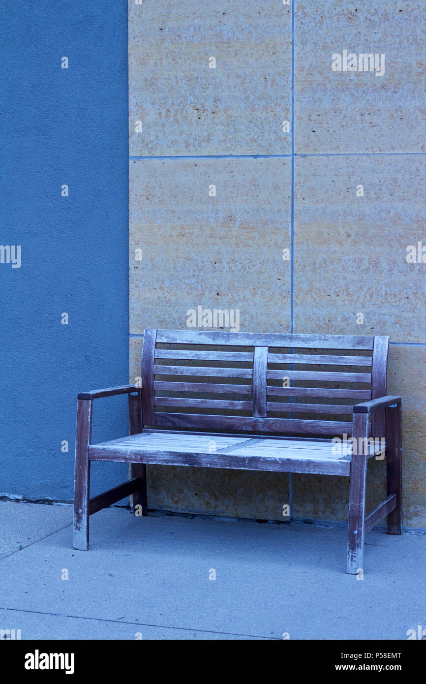 Shabby Chic Bank gegen eine blau und beige moderne Mauer aus Stein auf einer Stadt Bürgersteig set vermittelt ein kühles monochromatischen suchen Stockfoto