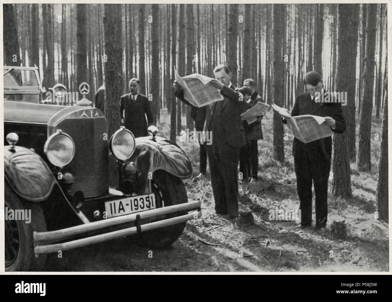 Adolf Hitler und Entourage steht neben seinem Mercedes beim Lesen der Zeitungen im Wald, Deutschland, Anfang der 30er Jahre Stockfoto