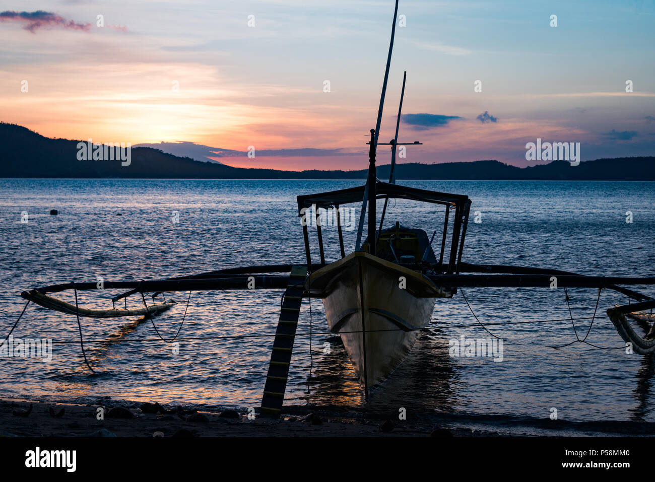 Traditionelle banca Boote am Ufer bei Sonnenuntergang, Anilao, Philippinen Stockfoto