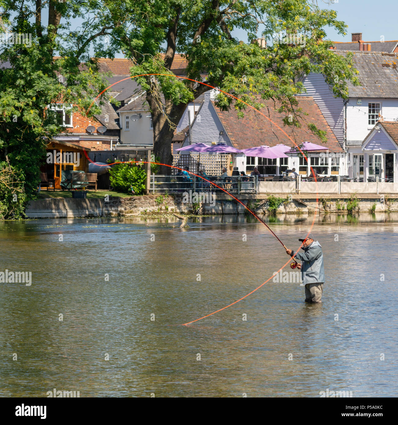 Fordingbridge, Hampshire, Großbritannien, Fisherman hält sich bei heißem Wetter kühl, indem man im kühlen Wasser des Flusses Avon steht und mit einer Angelschnur wirft. Stockfoto