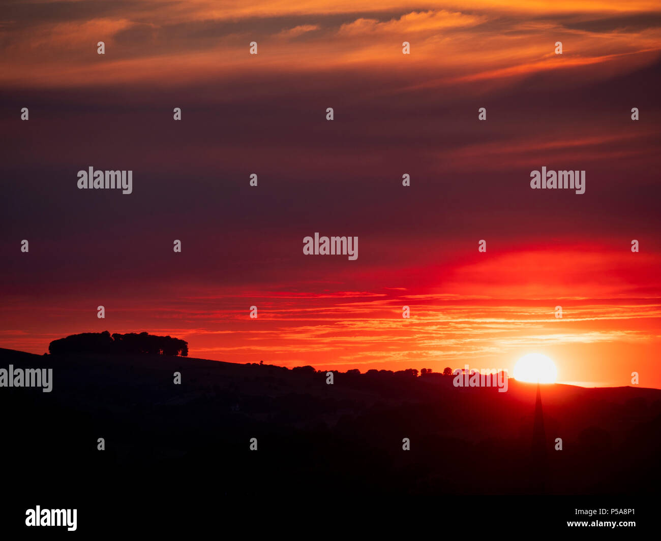 Ashbourne, Derbyshire, UK. 26 Juni, 2018. UK Wetter: spektakulären Sonnenuntergang über Ashbourne Kirchturm & die alten Wälder Hazleton Büschel Cairn in der Nähe von Thorpe aus Ashbourne, Derbyshire Peak District National Park Credit: Doug Blane/Alamy Leben Nachrichten genommen Stockfoto