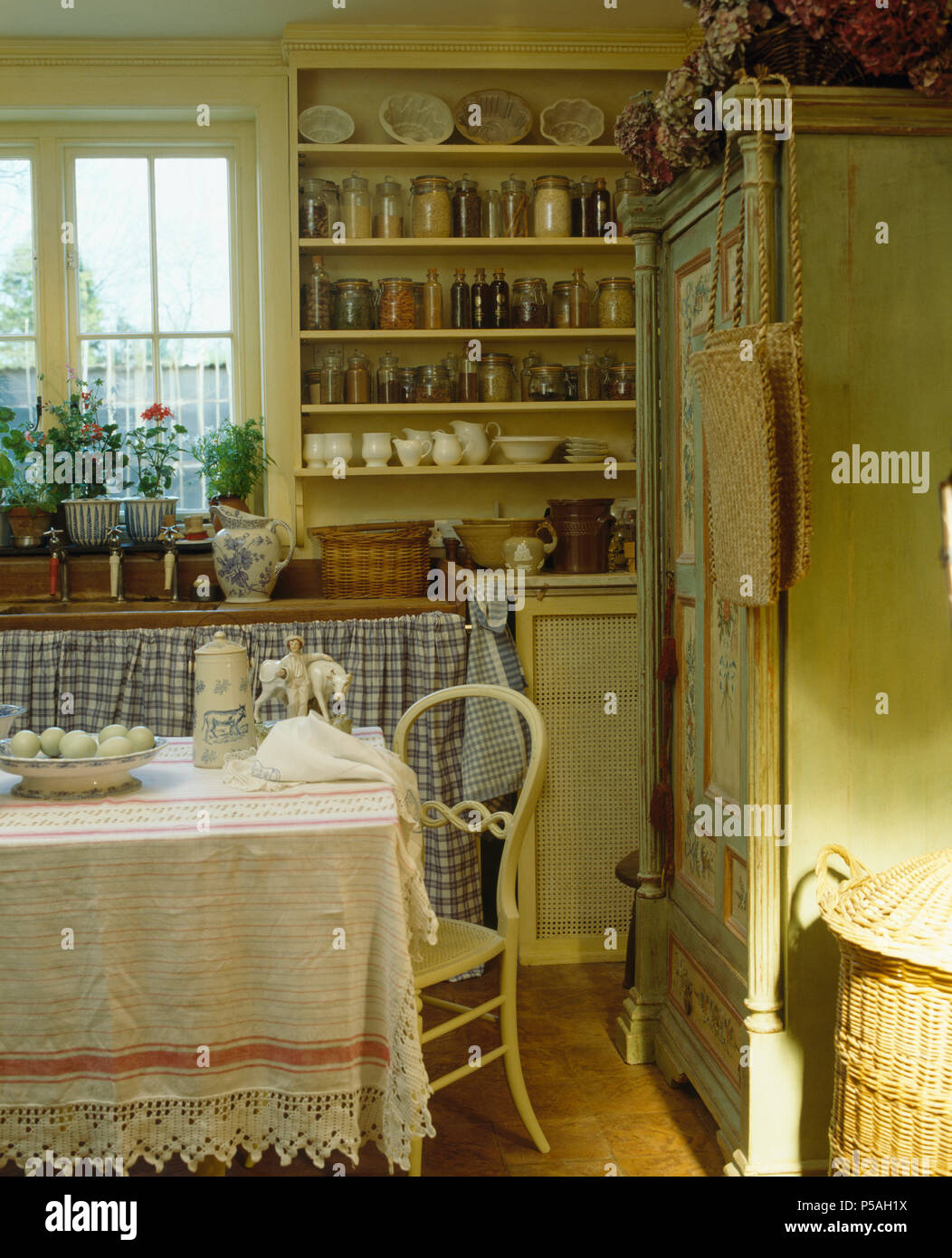 Storage jars Regal neben dem Fenster im Cottage Küche mit Spitze umrandet Tuch auf tabvle Stockfoto