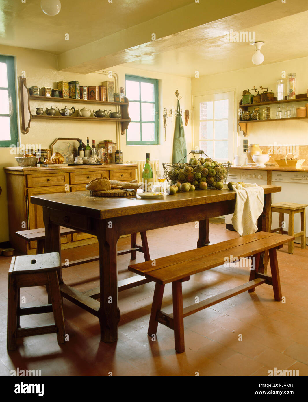 Holzbänke und alten Hocker bei einfachen Holztisch in Französisch Land Küche Stockfoto