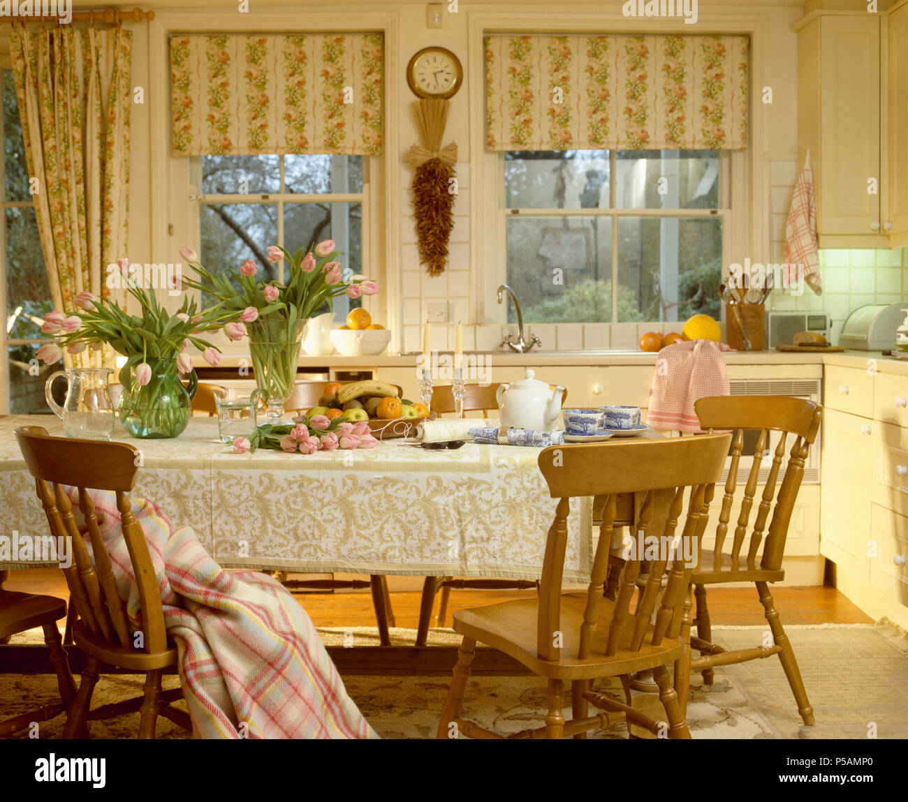Florale gestreifte blind auf Windows in der traditionellen Küche Esszimmer mit Kiefer Stühle am Tisch mit spitze Lappen Stockfoto