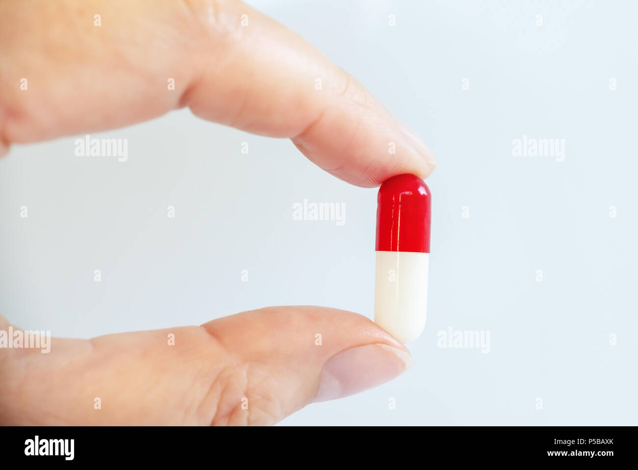 Nahaufnahme einer Hand, die eine weiße und rote Pille, Gesundheit und Medikamente Konzept Stockfoto