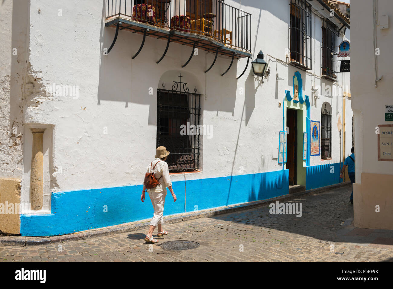 Frau mittleren Alters reist alleine, Blick auf eine Frau mittleren Alters, die eine Straße in der Altstadt von Cordoba, Andalusien, Spanien, erkundet. Stockfoto
