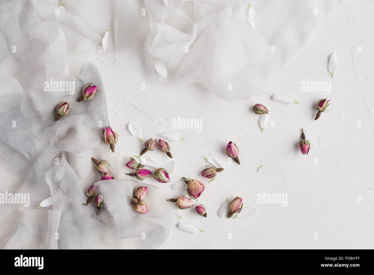 Weiß feminine Hintergrund mit weißer und grauer Seide, weißen Blüten und getrocknete Rosen. Platz kopieren, Schiefer Hintergrund oder Textur. Konzept. Stockfoto