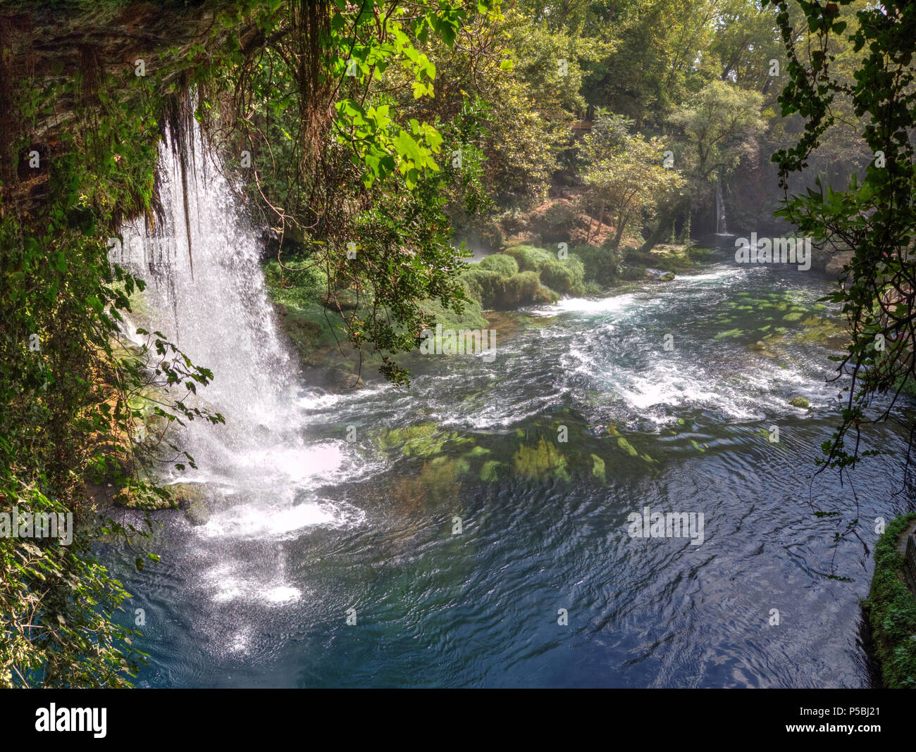 Majestätische Duden Wasserfälle in Antalya, Türkei, mit kaskadendem Wasser, das in ein breites Becken fließt, umgeben von üppigem Grün und lebendiger Naturlandschaft. Stockfoto