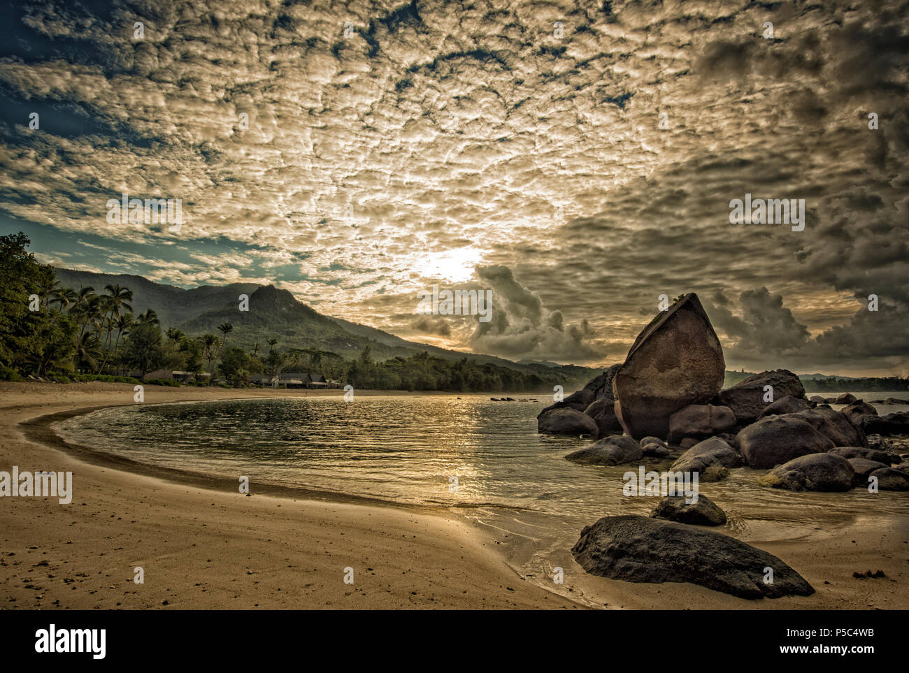 Ein Sonnenaufgang in Grand Anse Seychellen erzeugen eine ruhige Stimmung mit den frühen Morgen weichen Sonnenstrahlen durch die Makrele Himmel peeping Stockfoto