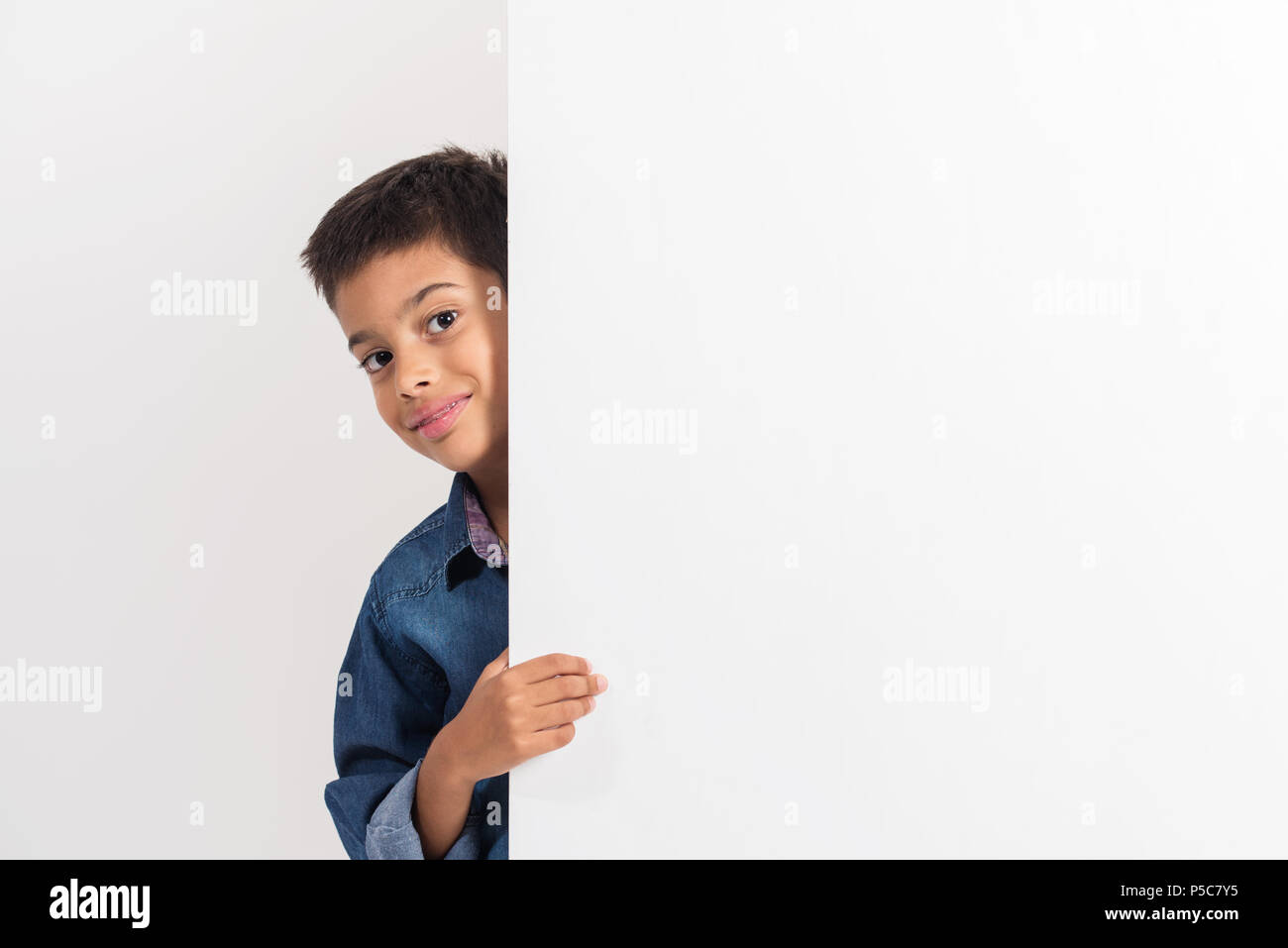 Portrait Of Happy little boy Holding ein leeres Brett gegen weißen Hintergrund. Stockfoto