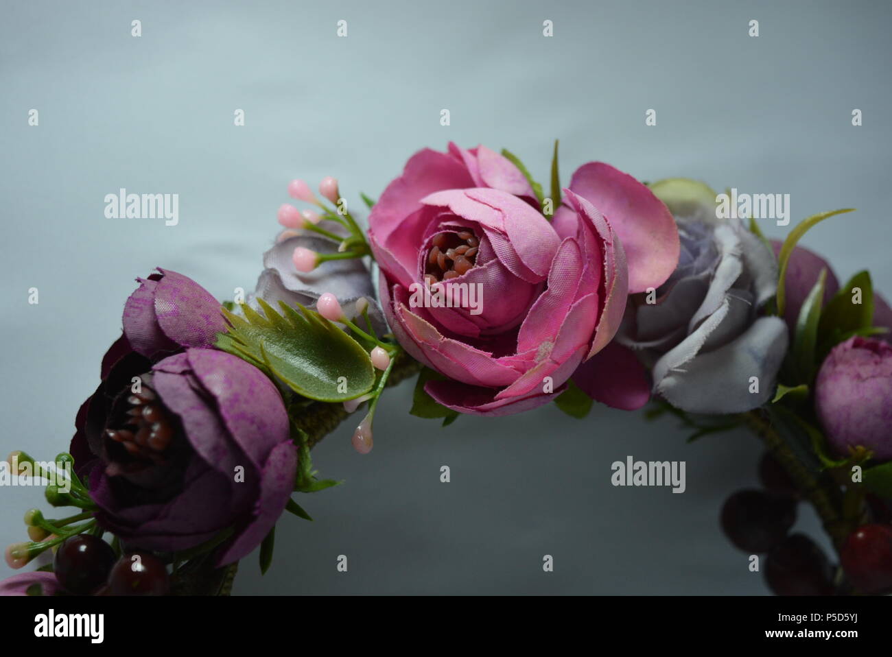 Interessante Haardekoration für Frauen, festlicher Look. Schöner Kopfreif aus violetten, rosa Blüten, Pfingstrosen und grünen Blättern mit roten Beeren platziert Stockfoto