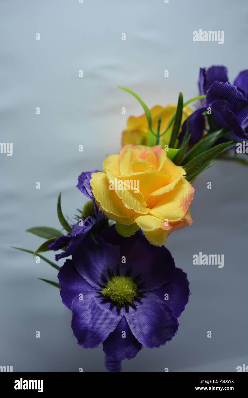 Interessante Haardekoration für Frauen, festlicher Look. Schöner Kopfreif aus blauen, gelben Blumen und grünen Blättern auf weißem Hintergrund. Stockfoto