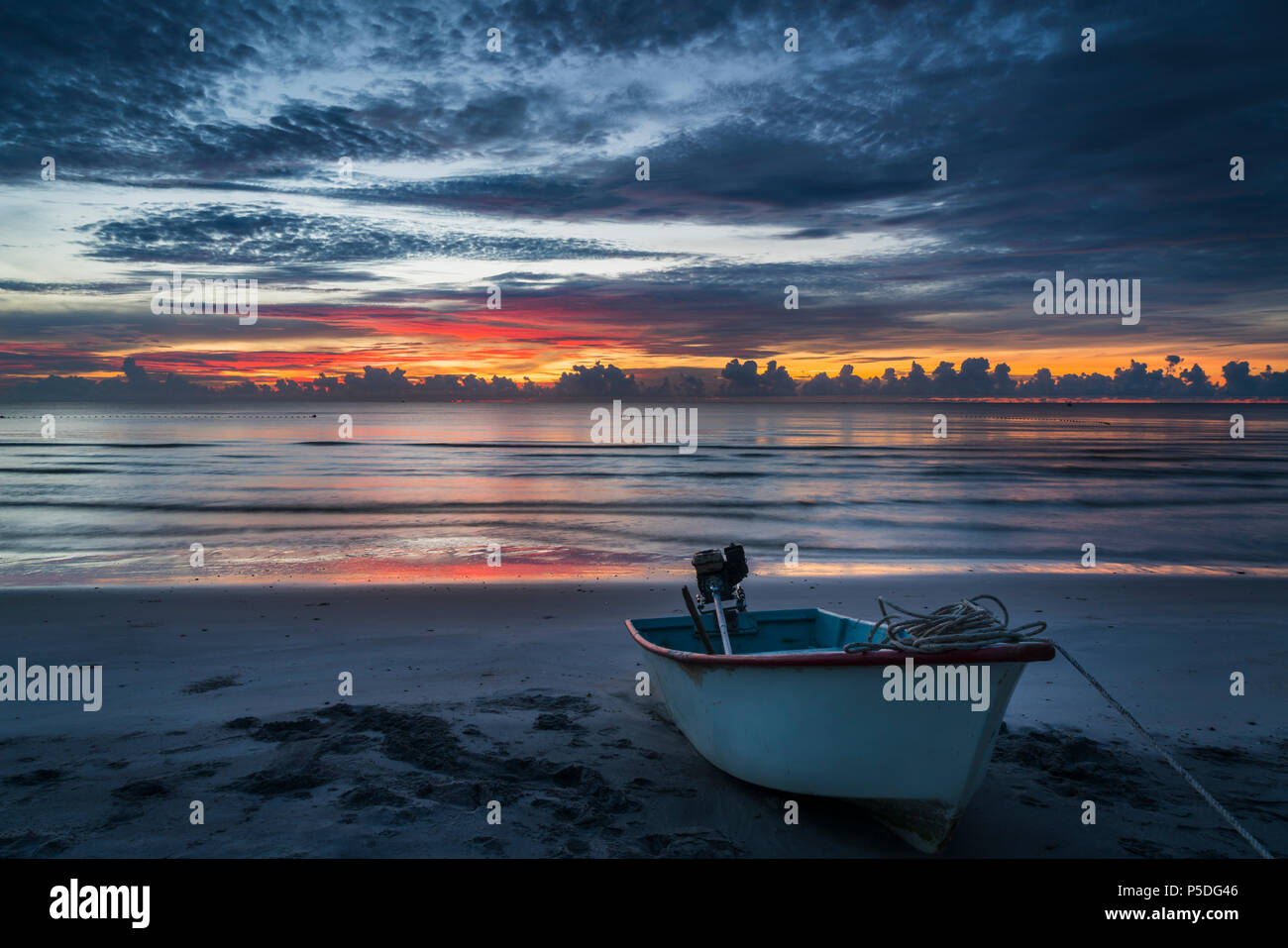 Eine wunderschöne tropische Dämmerung mit einem Boot am Strand. Stockfoto