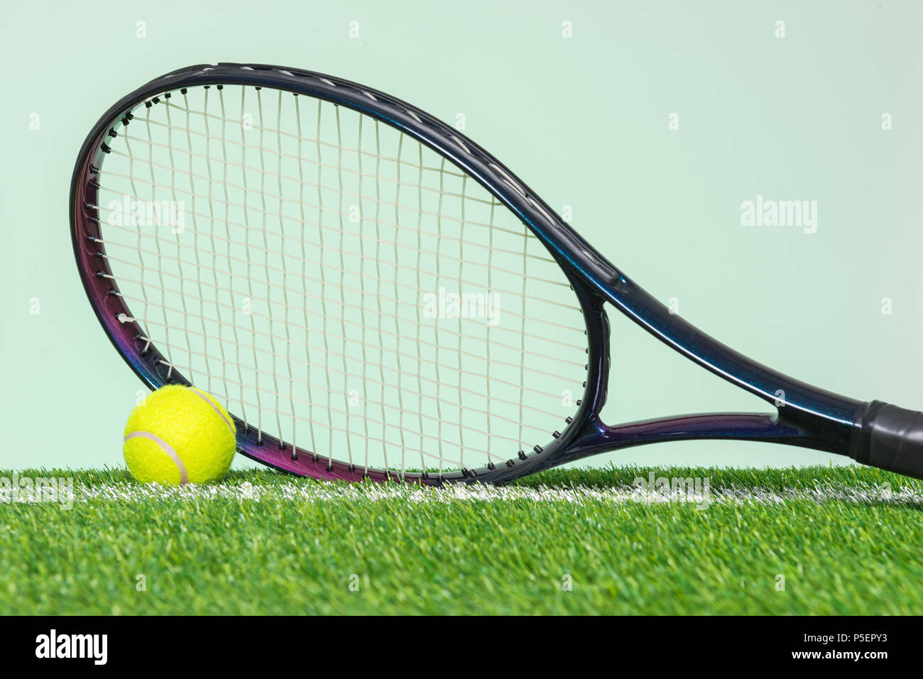 Ein Tennisschläger und Ball auf Gras mit einfachen grünen Hintergrund. Stockfoto