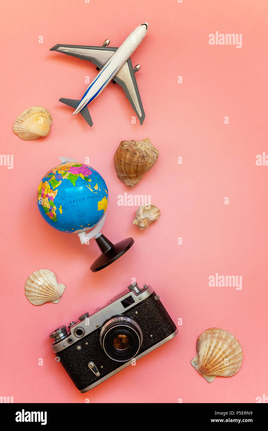 Flach mit Flugzeug, Vintage film Foto Kamera, Globus und Shell auf Rosa farbenfrohen Pastelltönen Trendy Modern Fashion Hintergrund. Ferienhäuser Reisen Sommer Stockfoto