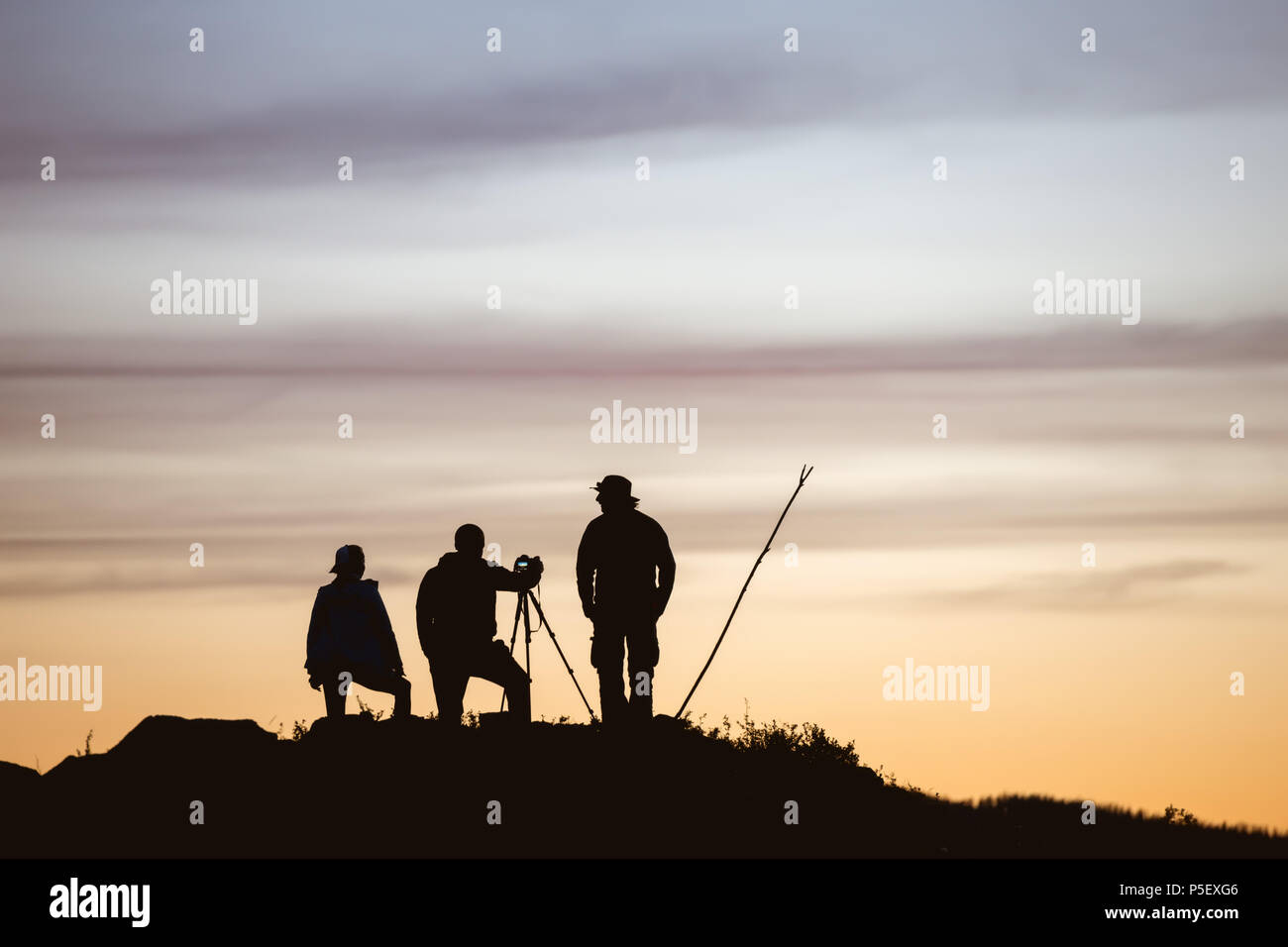 Gruppe von Fotografen steht gegen Sonnenuntergang Himmel und unter Foto mit Stativ Stockfoto