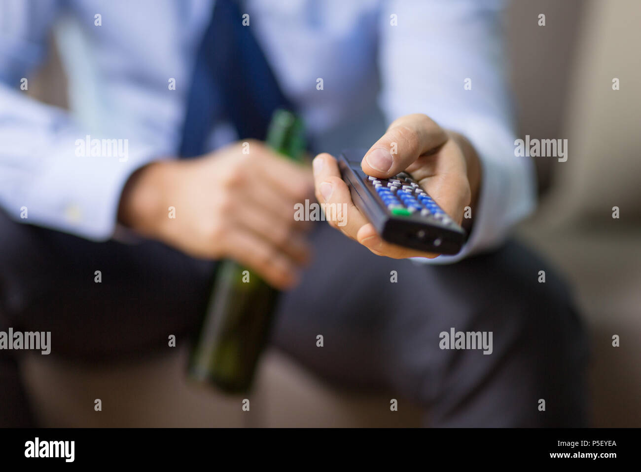 Nahaufnahme der Mann mit der TV-Fernbedienung, Bier trinken. Stockfoto