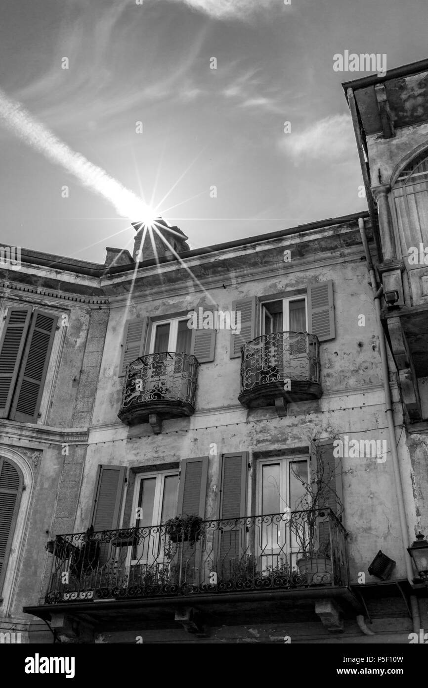 Visuelle Illusionen der Sonne Eingabe eines Hauses durch den Schornstein in Norditalien. Flugzeug Kondensstreifen. Street View, schwarz-weiß-Bild. Stockfoto