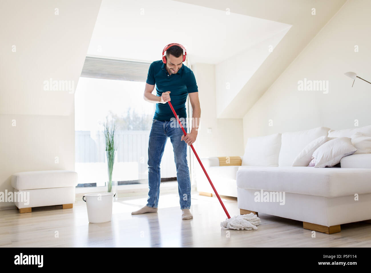 Mann in Kopfhörer Reinigung Boden von mop zu Hause Stockfoto