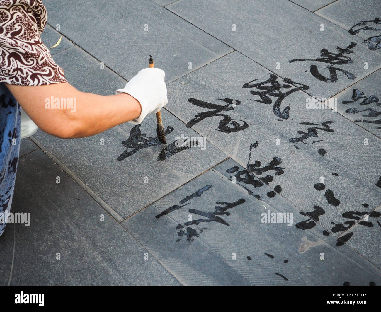 Ältere Frau üben Kalligraphie und Schrift' Hui Feng Chang'er Sinne eine sanfte und angenehme Brise, Peking, China Stockfoto