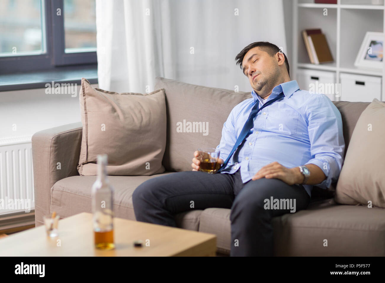 Betrunkener Mann mit einem Glas Alkohol schlafen zu Hause Stockfoto