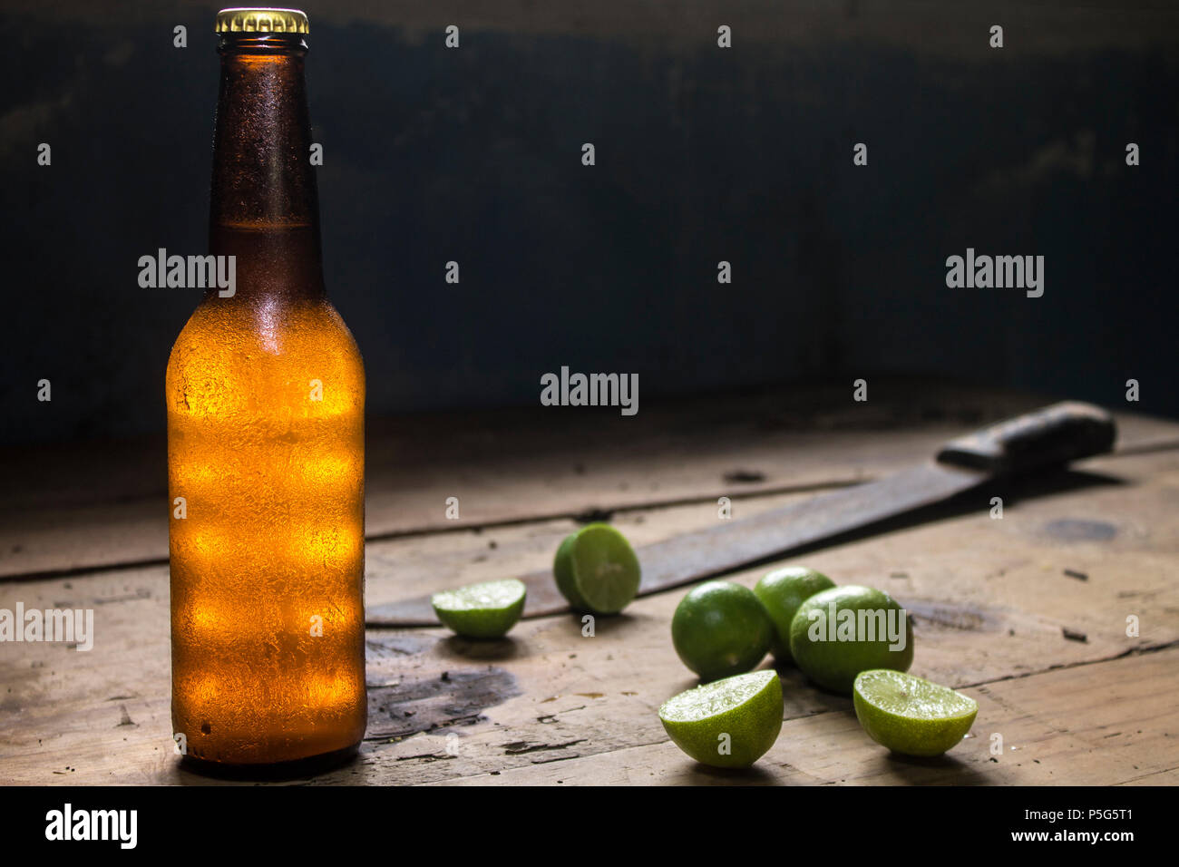 Kalte Flasche Bier und Zitronen auf einem rustikalen Holztisch, Machete, Mexiko Stockfoto