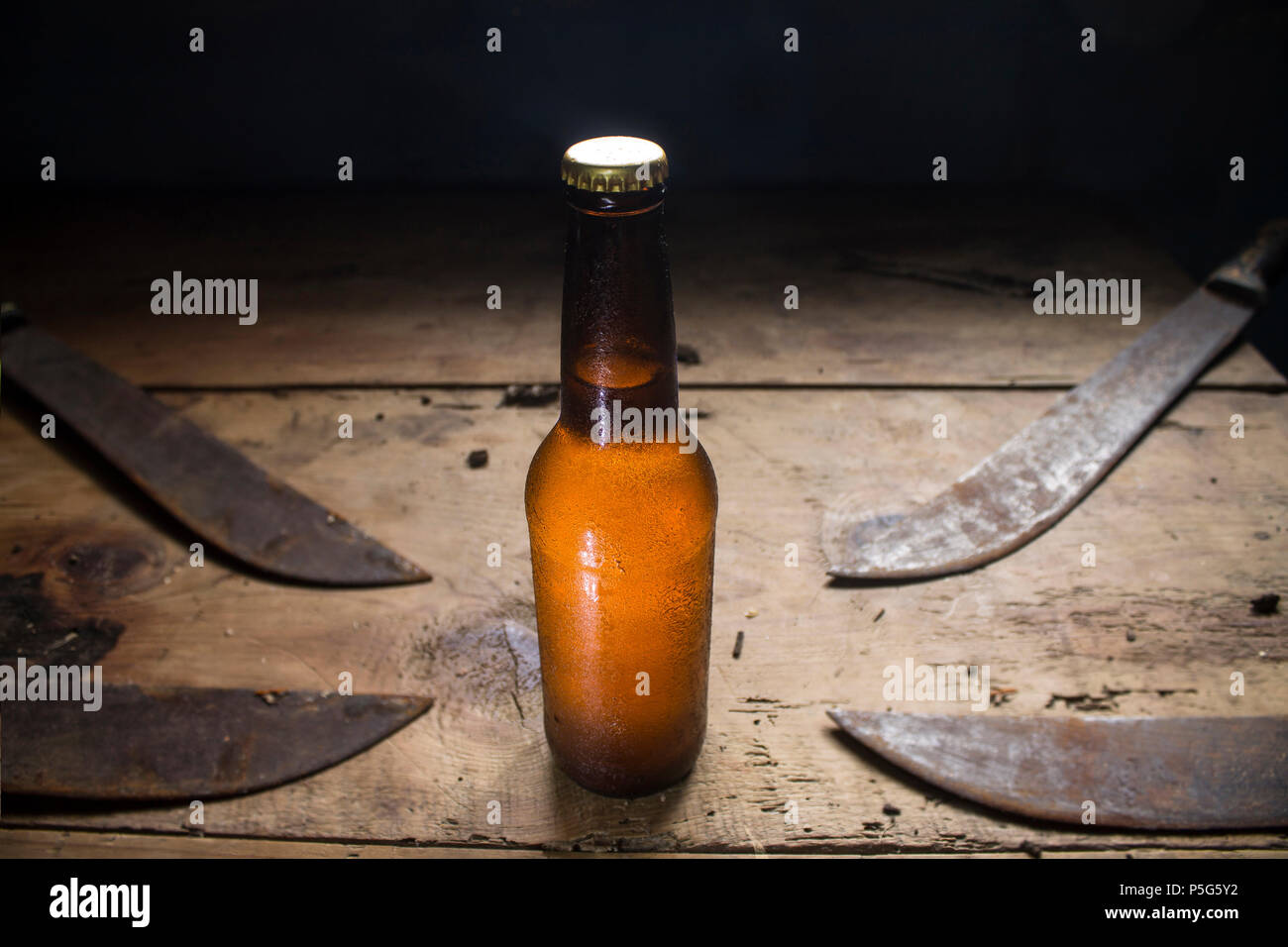 Kalte Flasche Bier mit vier Macheten auf einem rustikalen Holztisch, mexikanischen Stockfoto