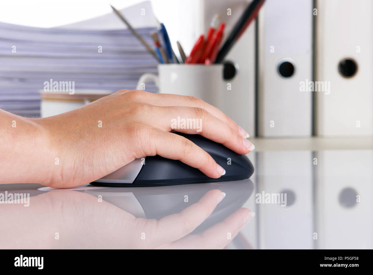 Weibliche Hand auf einem Computer Maus, vor dem Hintergrund von Dateien und Unterlagen Stockfoto
