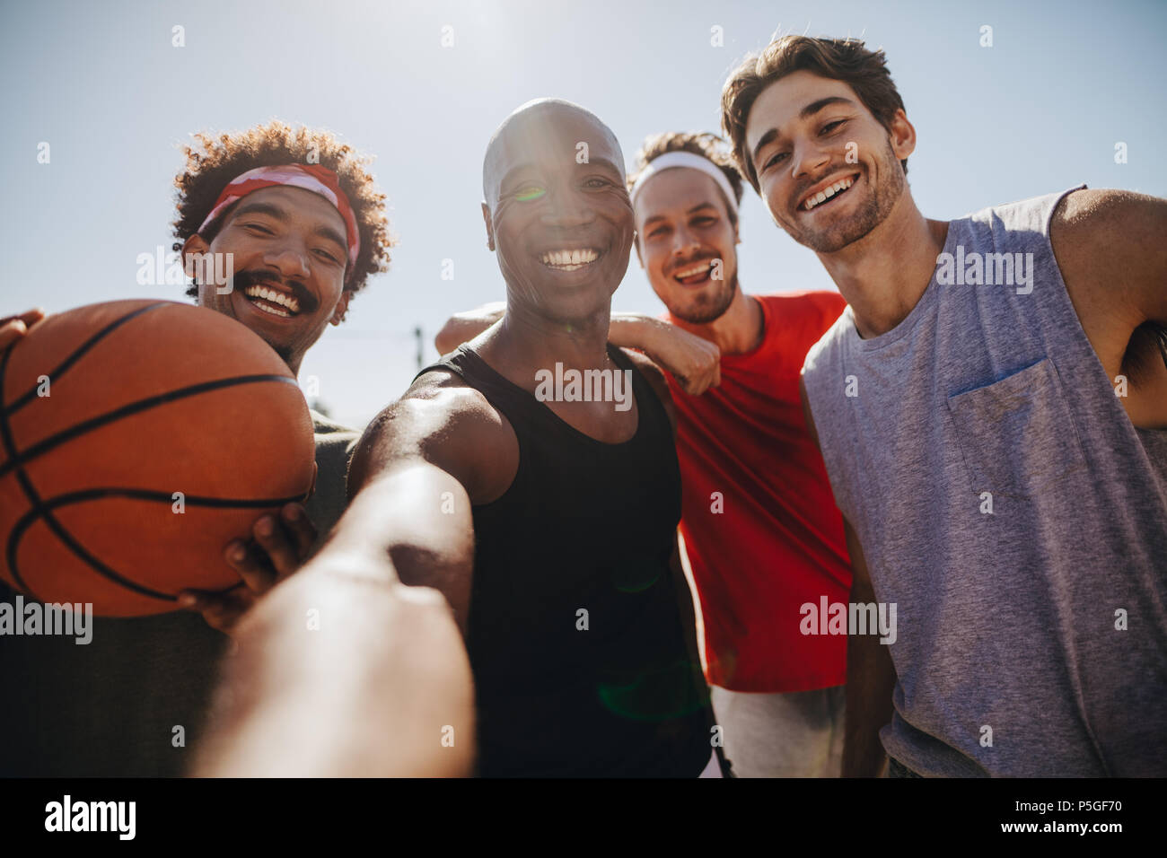 Vier Männer für selfie Holding ein Basketball posieren. Lächelnd Athleten genießen, während Basketball spielen. Stockfoto