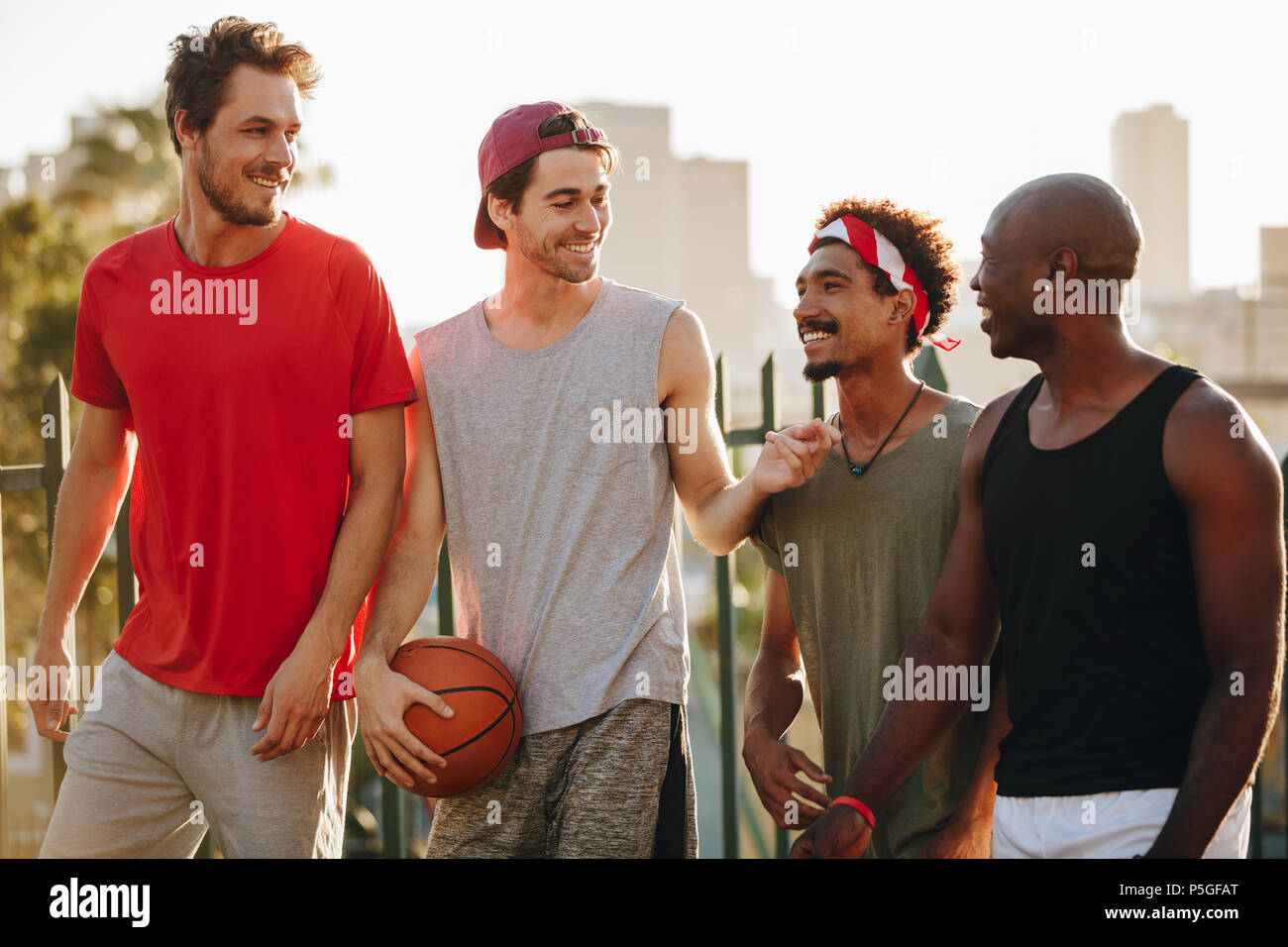 Vier fröhlichen Basketball Männer gehen auf Pflaster sprechen. Männer zu Fuß zurück nach einem Spiel der Basketball. Stockfoto