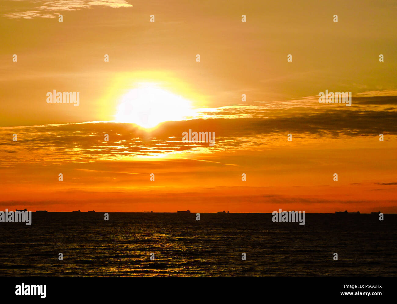 Leuchtend gelbe Sonnenaufgang über dem Golf von Mexiko silhouetting Schiffe aufgereiht am Horizont Stockfoto