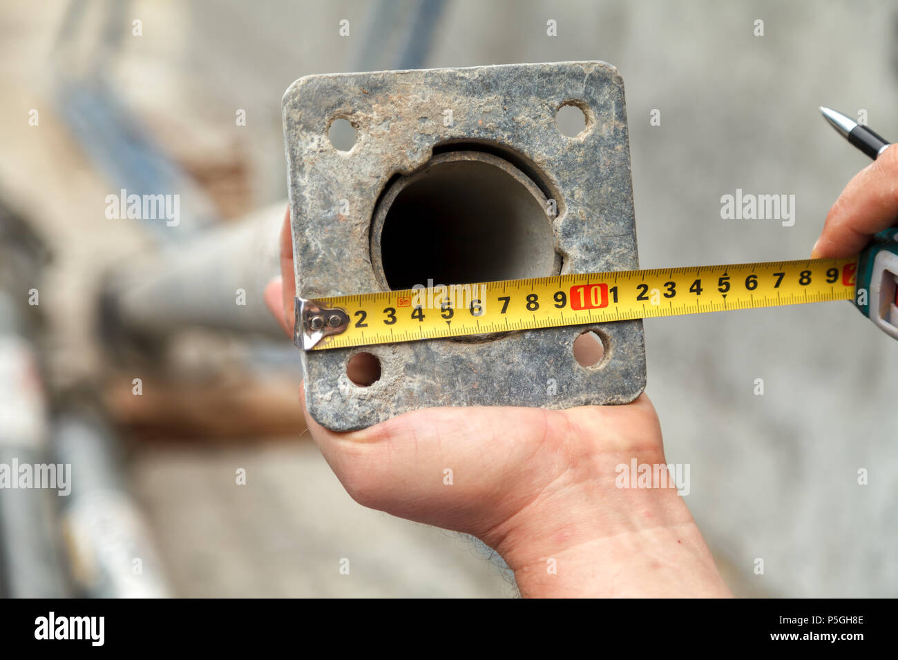 Die Builder unterstützt ein metallstück mit einer Hand, und in der zweiten Hand hält ein Maßband messen, welche Messungen macht Stockfoto