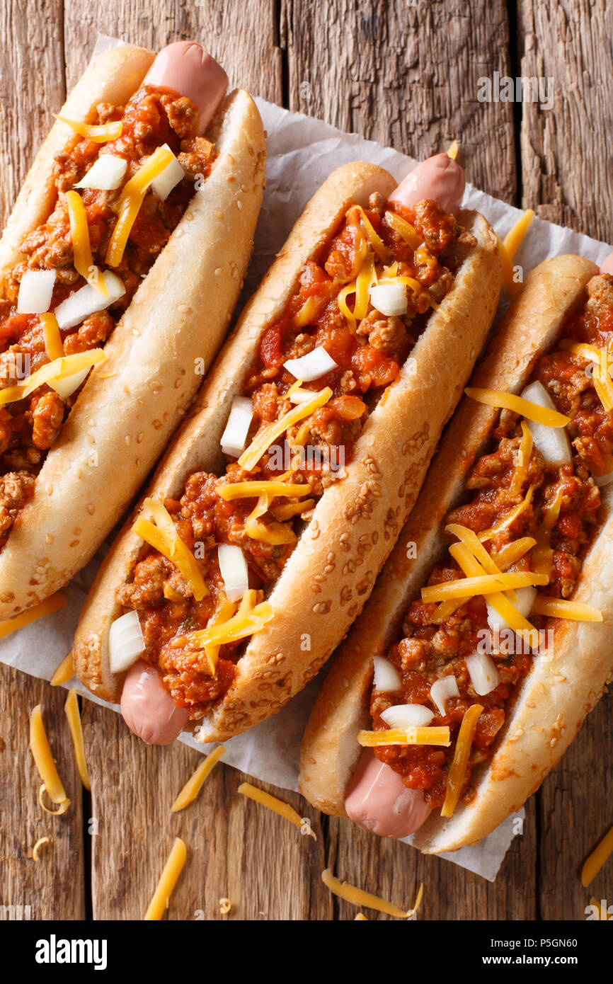 Chili Hot Dog mit Cheddar Käse und pikanter Sauce close-up auf Tisch. Senkrechte Draufsicht von oben Stockfoto
