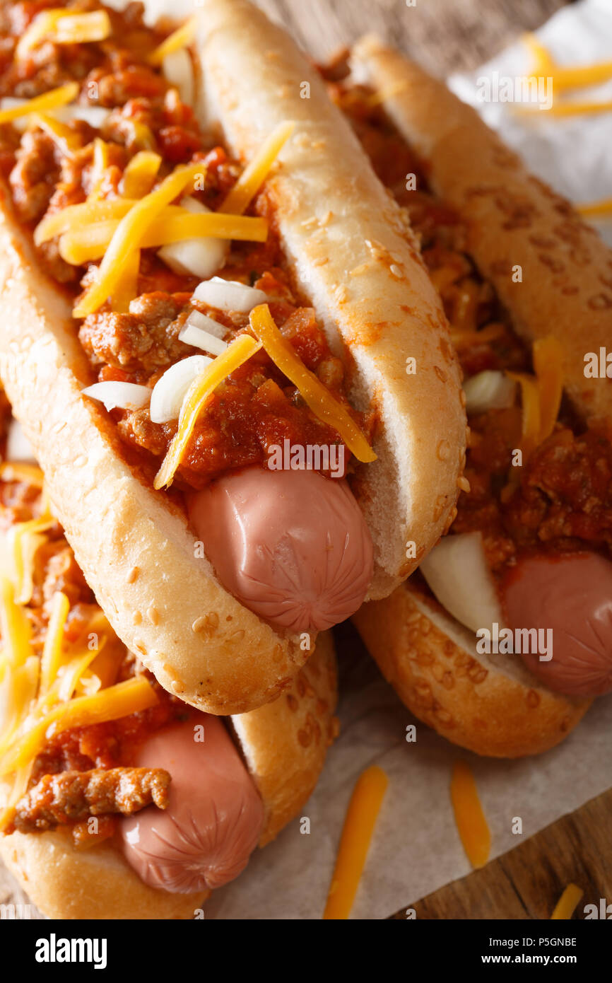 Chili Hot Dog mit Cheddar Käse und pikanter Sauce close-up auf Tisch. Vertikale Stockfoto