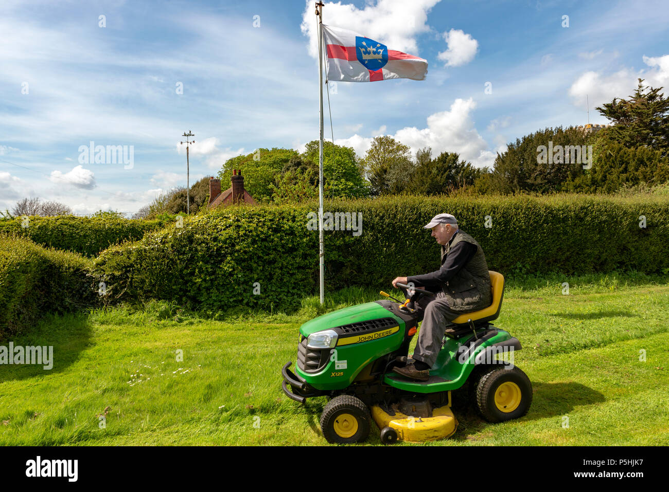 Älterer Mann mit aufsitzendem Rasenmäher, Bawdsey, Suffolk, England. Stockfoto