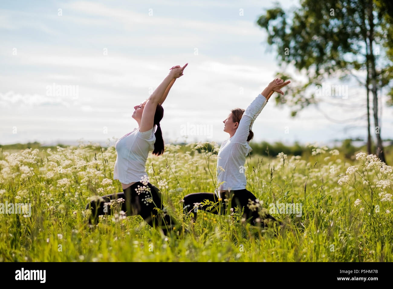 Zwei junge Frauen üben yoga Outdoor im Park. Stockfoto